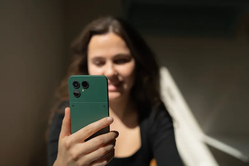 Eine Frau hält ein grünes Fairphone Gen. 6 in der Hand