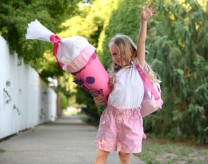 Ein fröhliches, blondes Mädchen mit pinker Schultüte in der Hand