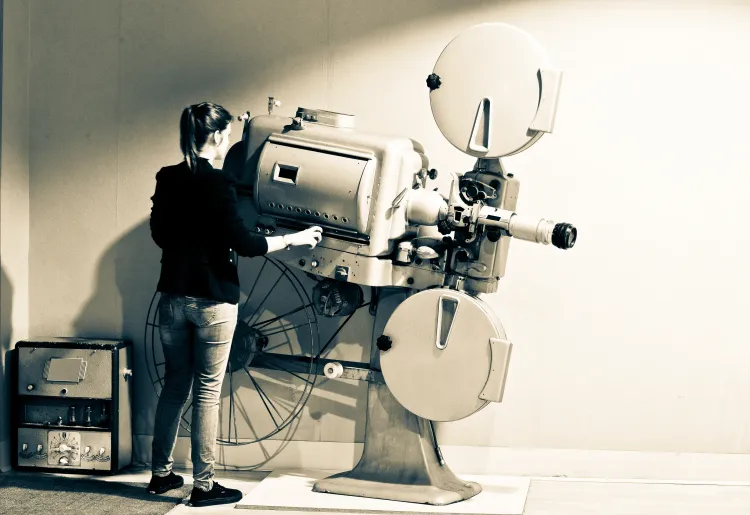 Frau bedient einen Filmprojektor.