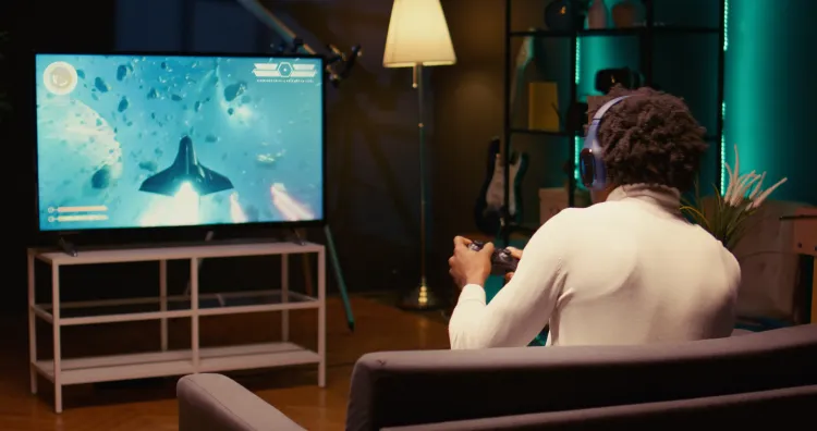 Gamer mit Headset und Controller spielt am Fernseher.