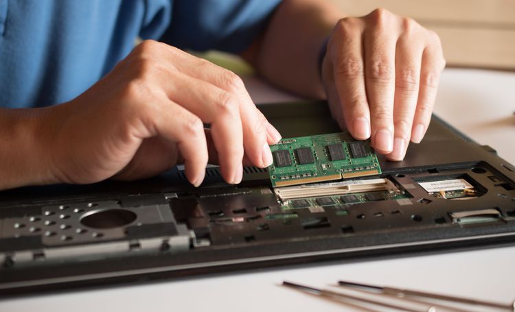Mann setzt RAM-Modul in Notebook ein