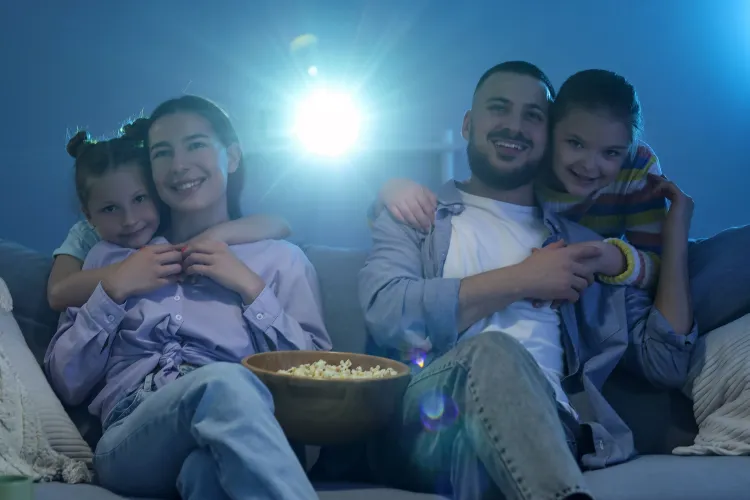 Junge Familie mit zwei kleinen Kindern schauen bei einer Beamerprojektion zu.