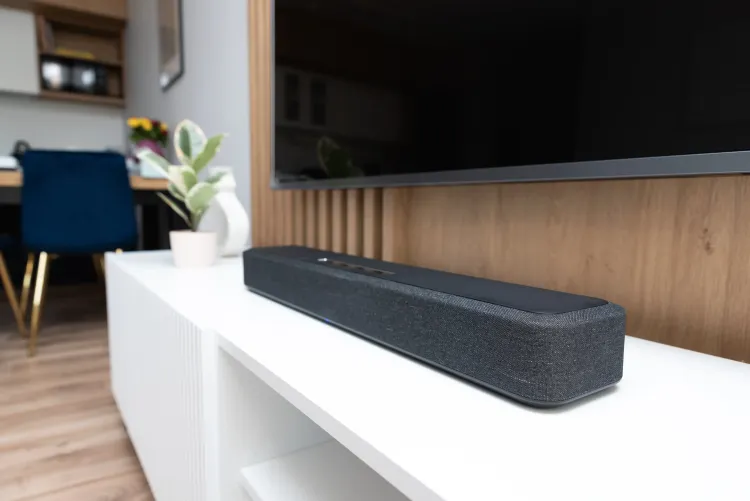 Unter einem an der Wand montierten Fernseher steht eine Soundbar auf einem Sideboard.