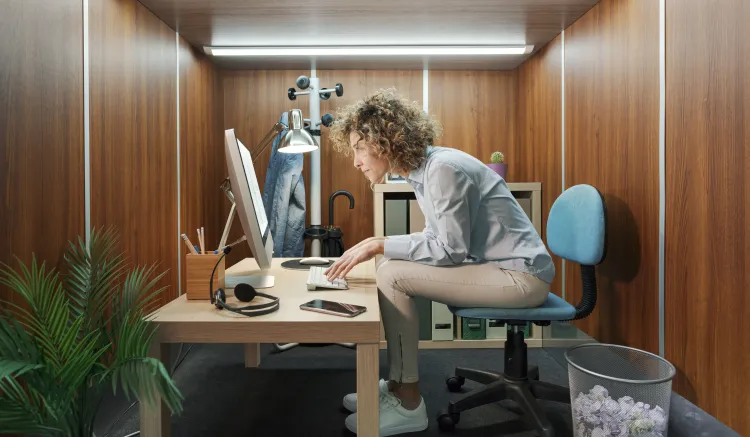 Frau arbeitet in einem viel zu kleinen Büro.