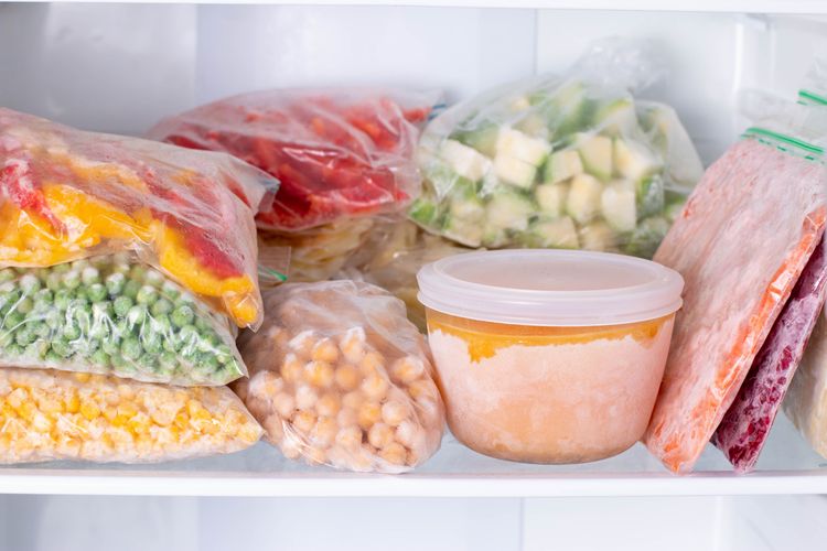 verschiedene Plastikbeutel mit buntem gefrorenem Gemüse in offenem Gefrierschrank
