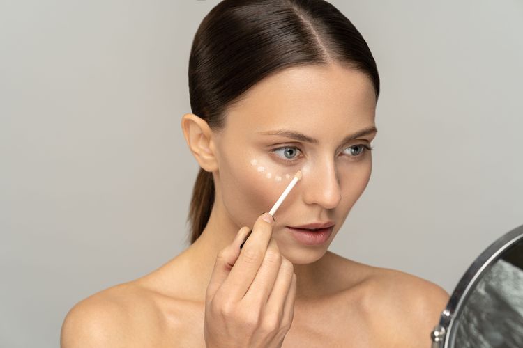 Frau trägt Concealer auf