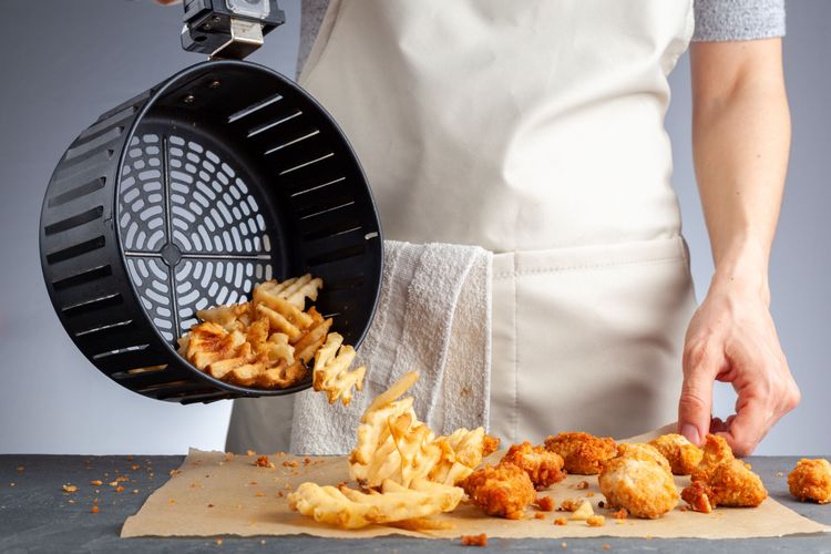 Person leert Frittiertes aus Frittierkorb
