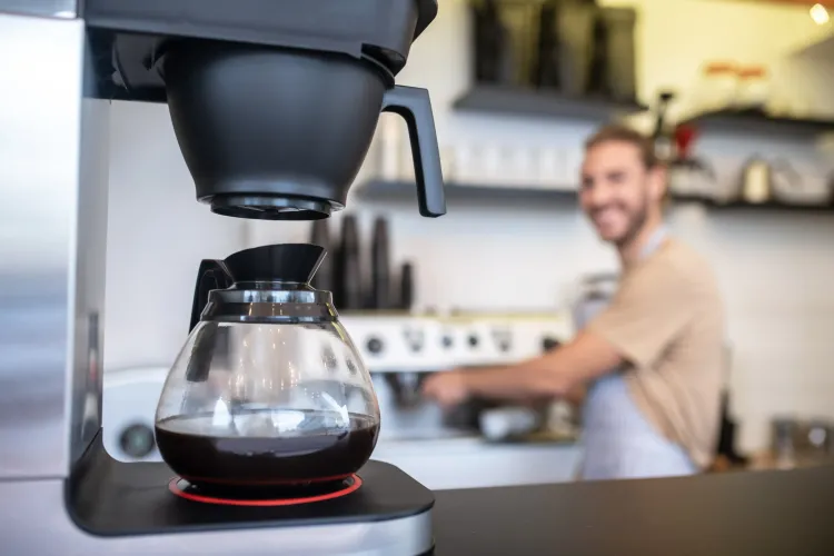 Filterkaffeemaschine mit Barista im Hintergrund