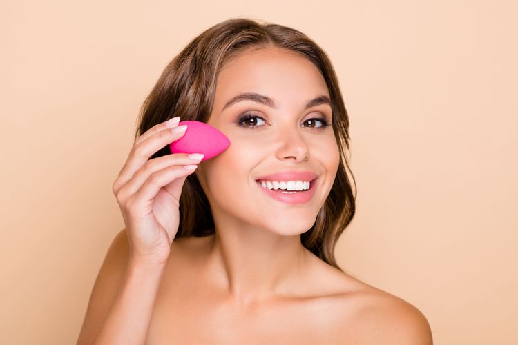 Frau trägt Foundation mit Beautyschwamm auf