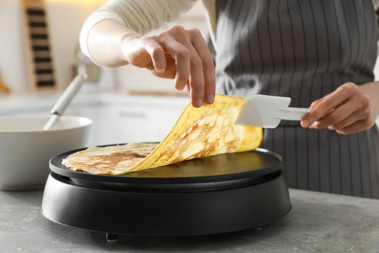 Person wendet Crepe auf Crepes Maker 