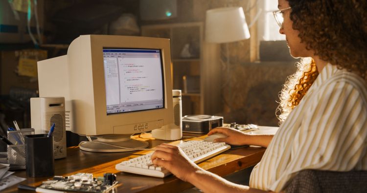 Junge Frau arbeitet an einem Desktop-PC aus den 90er Jahren.