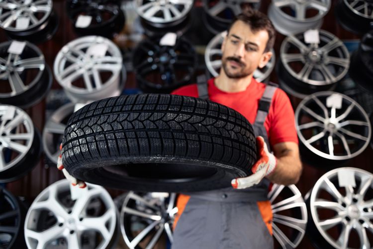Mechaniker hebt Ganzjahresreifen