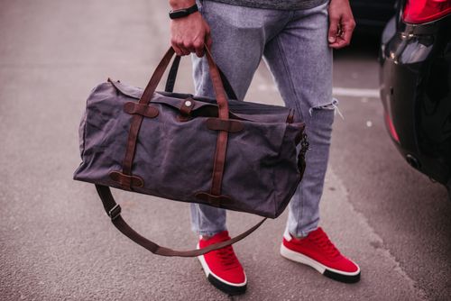 Person mit Reisetasche in der Hand